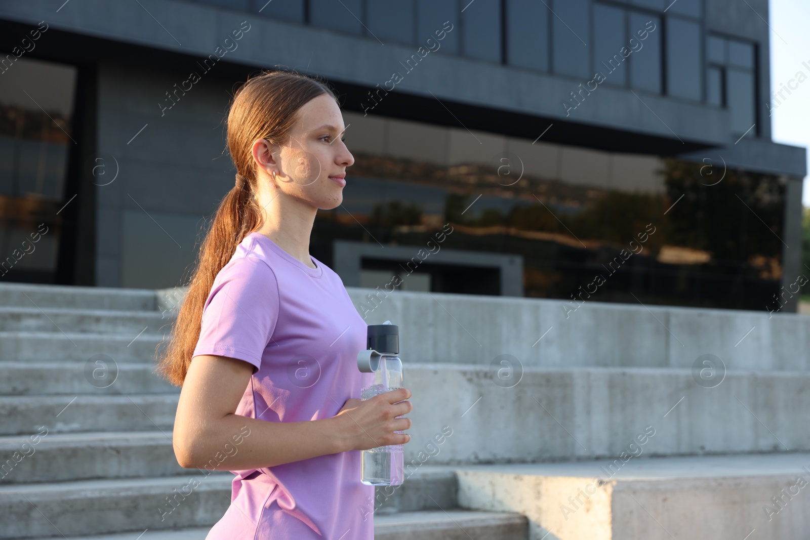 Photo of Teenage girl with water bottle after training outdoors. Space for text