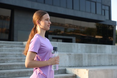Photo of Teenage girl with water bottle after training outdoors. Space for text