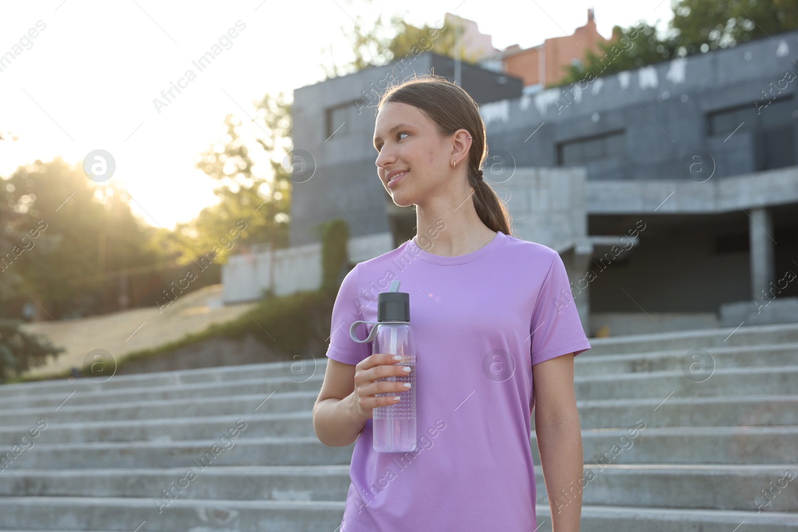 Photo of Teenage girl with water bottle after training outdoors. Space for text