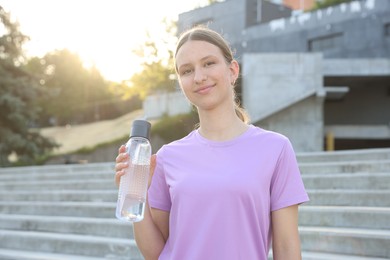Photo of Teenage girl with water bottle after training outdoors