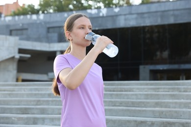 Photo of Teenage girl drinking water during training outdoors. Space for text