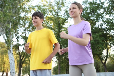 Photo of Teenage girl and boy running in park