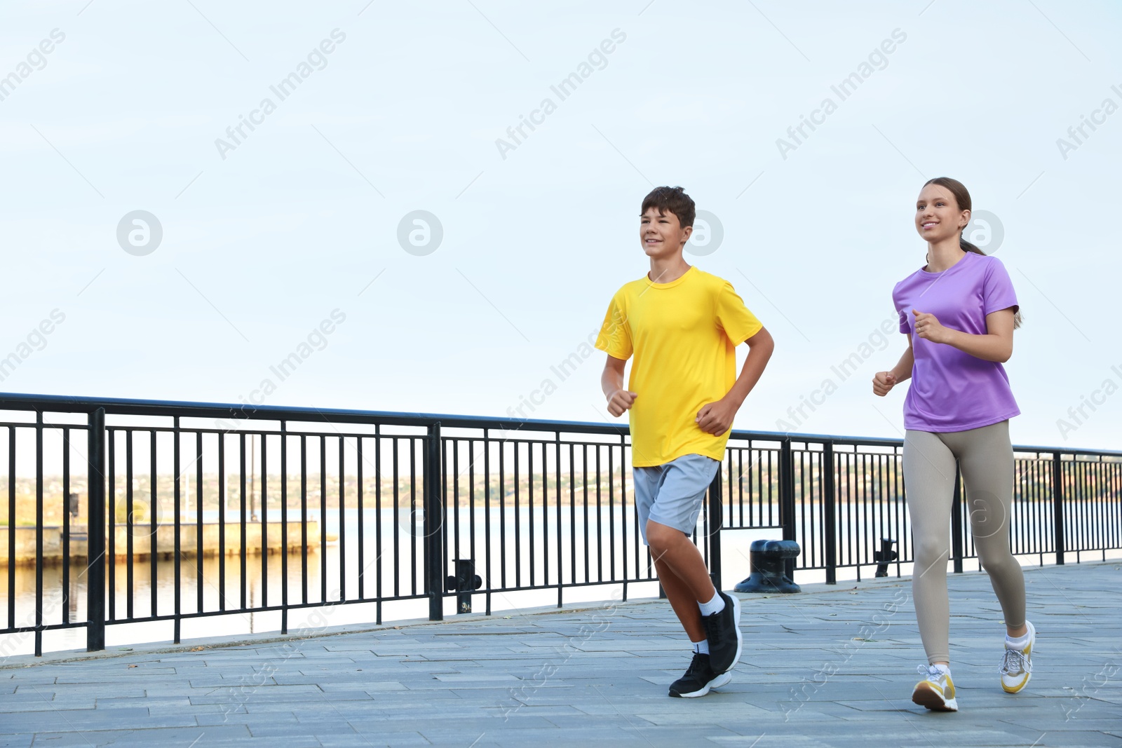 Photo of Teenage girl and boy running outdoors. Space for text