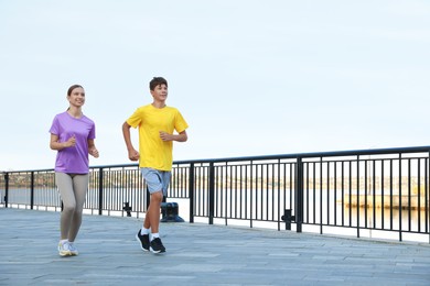 Photo of Teenage girl and boy running outdoors. Space for text