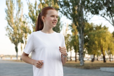 Photo of Teenage girl jogging in park. Morning run