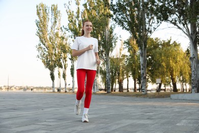 Photo of Teenage girl jogging in park. Morning run
