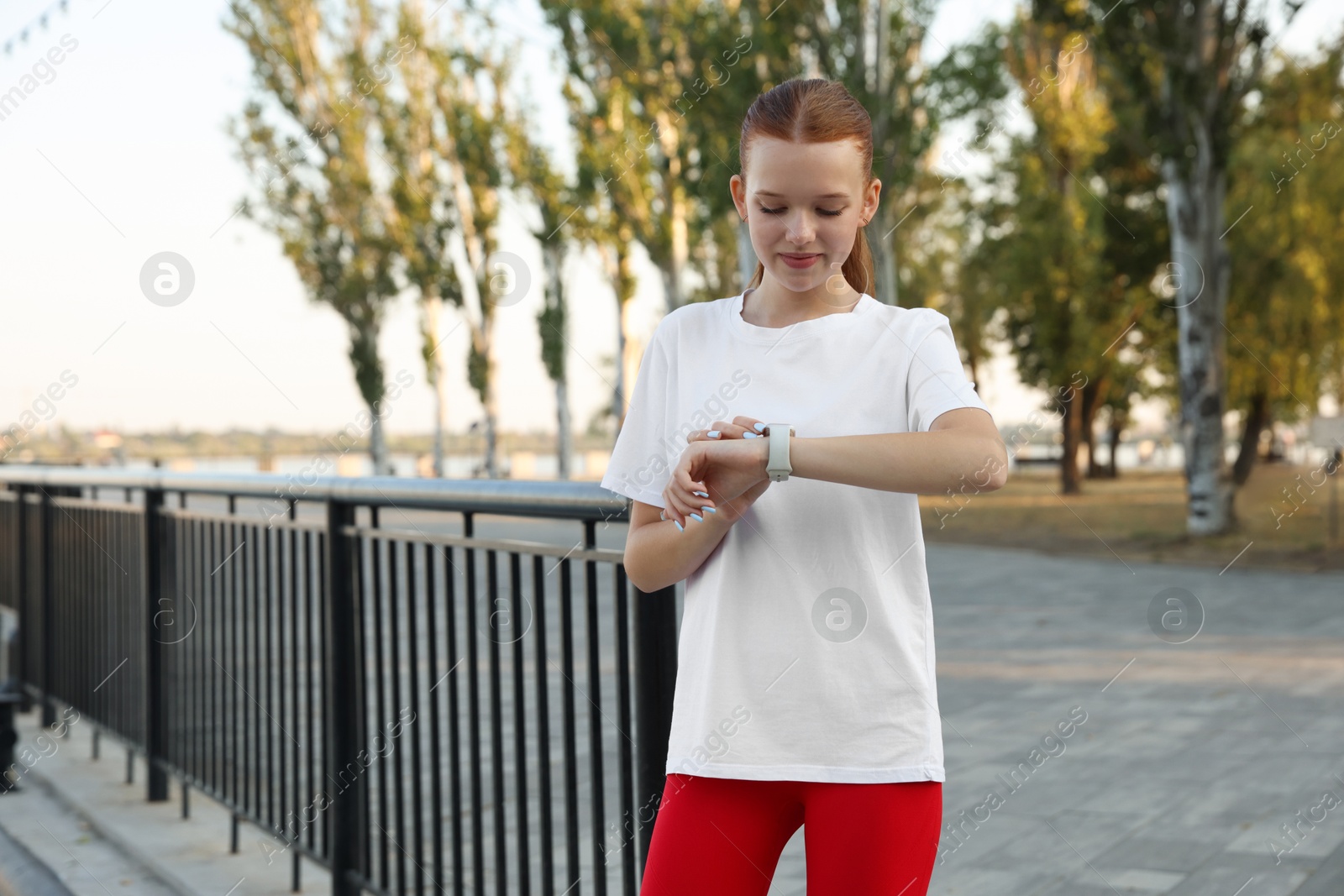 Teenage girl checking pulse via watch after training outdoors Photo of Teenage girl checking pulse via watch after training outdoors