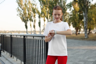 Photo of Teenage girl checking pulse via watch after training outdoors