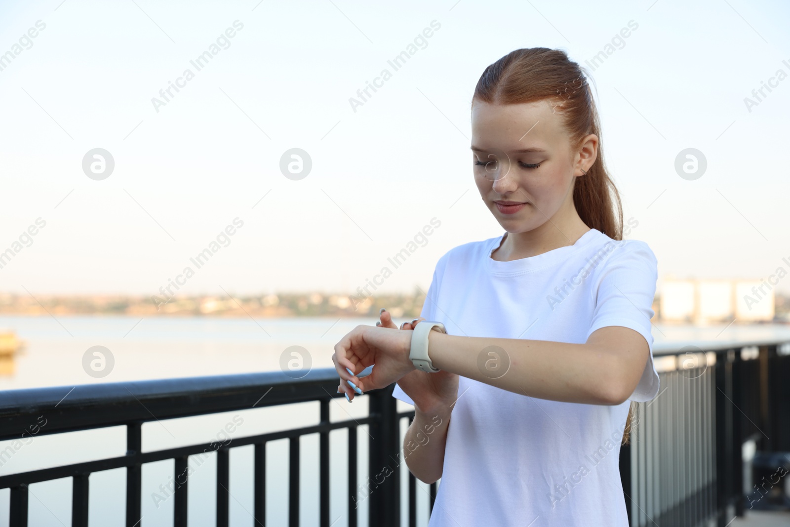Photo of Teenage girl checking pulse via watch after training outdoors. Space for text