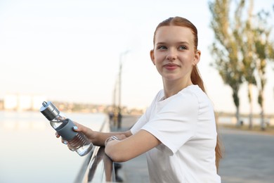 Photo of Teenage girl with water bottle after training outdoors