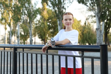 Photo of Teenage girl with water bottle after training outdoors. Space for text