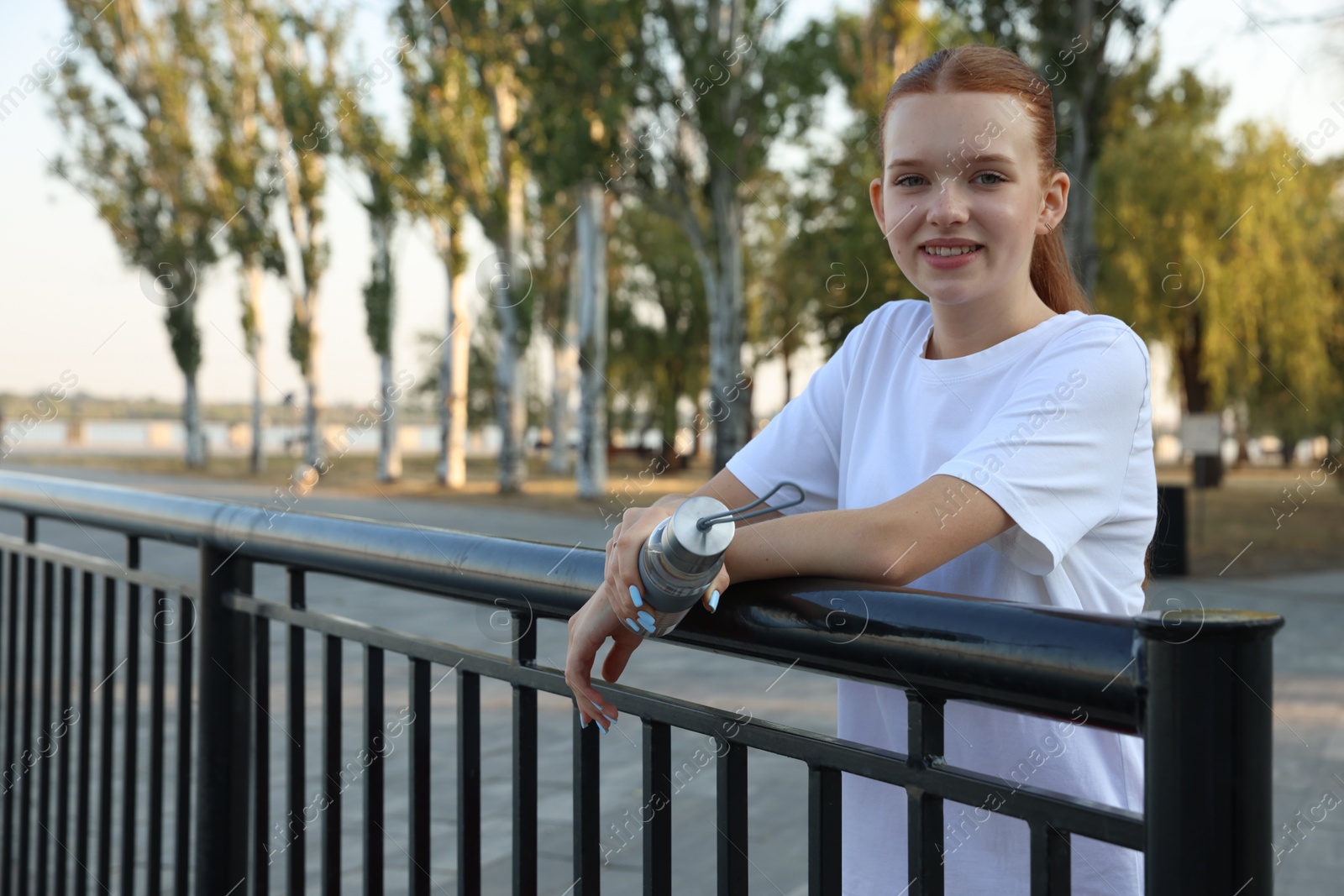 Teenage girl with water bottle after training outdoors. Space for text Photo of Teenage girl with water bottle after training outdoors. Space for text