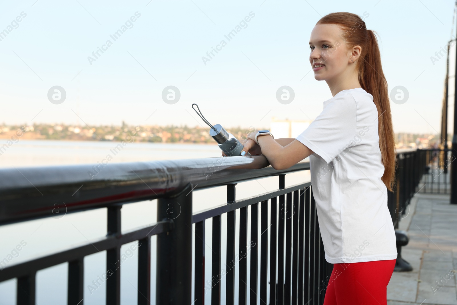 Photo of Teenage girl with water bottle after training outdoors. Space for text