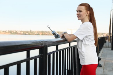 Photo of Teenage girl with water bottle after training outdoors. Space for text