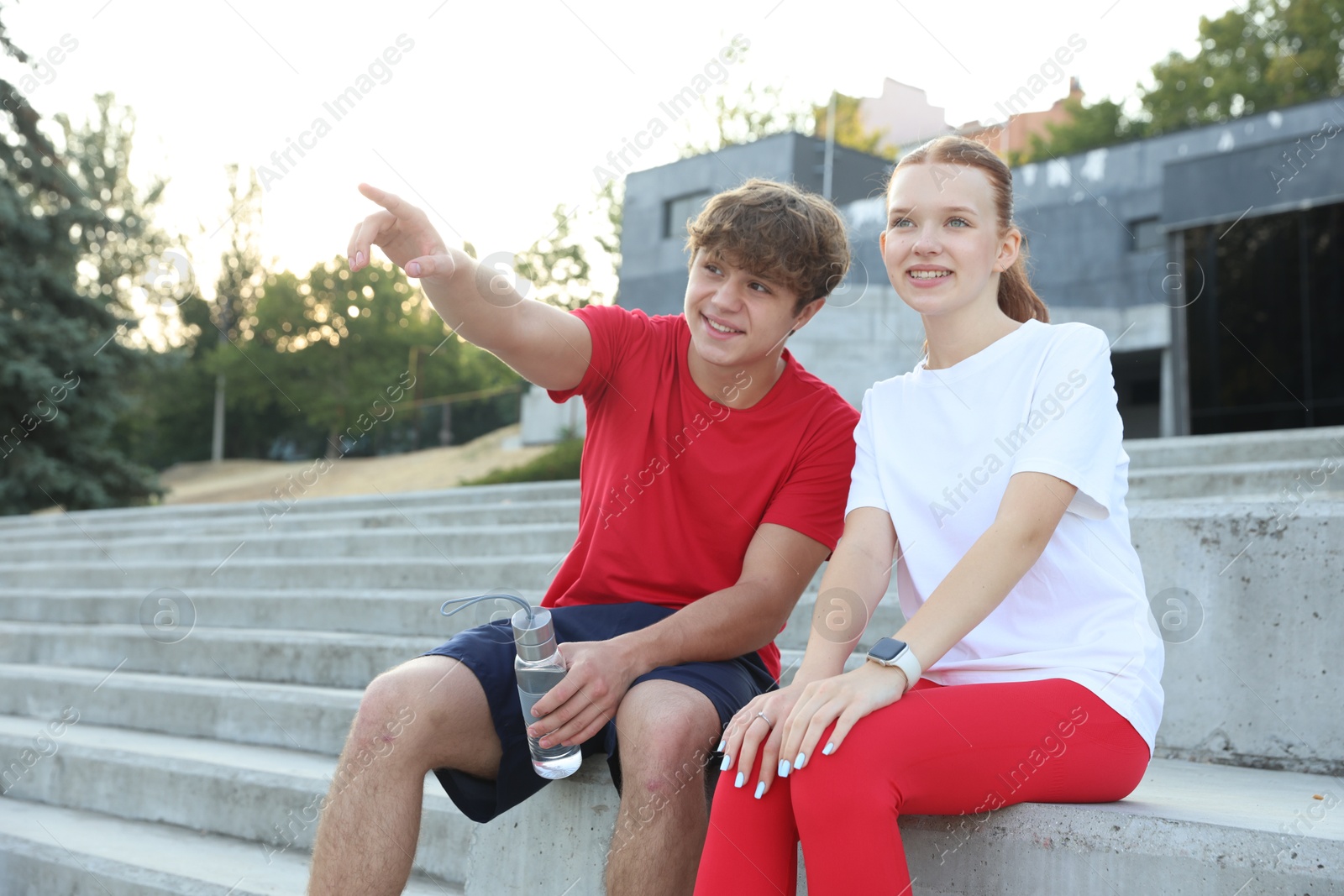 Teenage boy showing his friend something after training outdoors Photo of Teenage boy showing his friend something after training outdoors