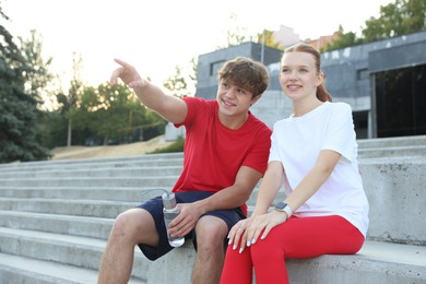 Photo of Teenage boy showing his friend something after training outdoors