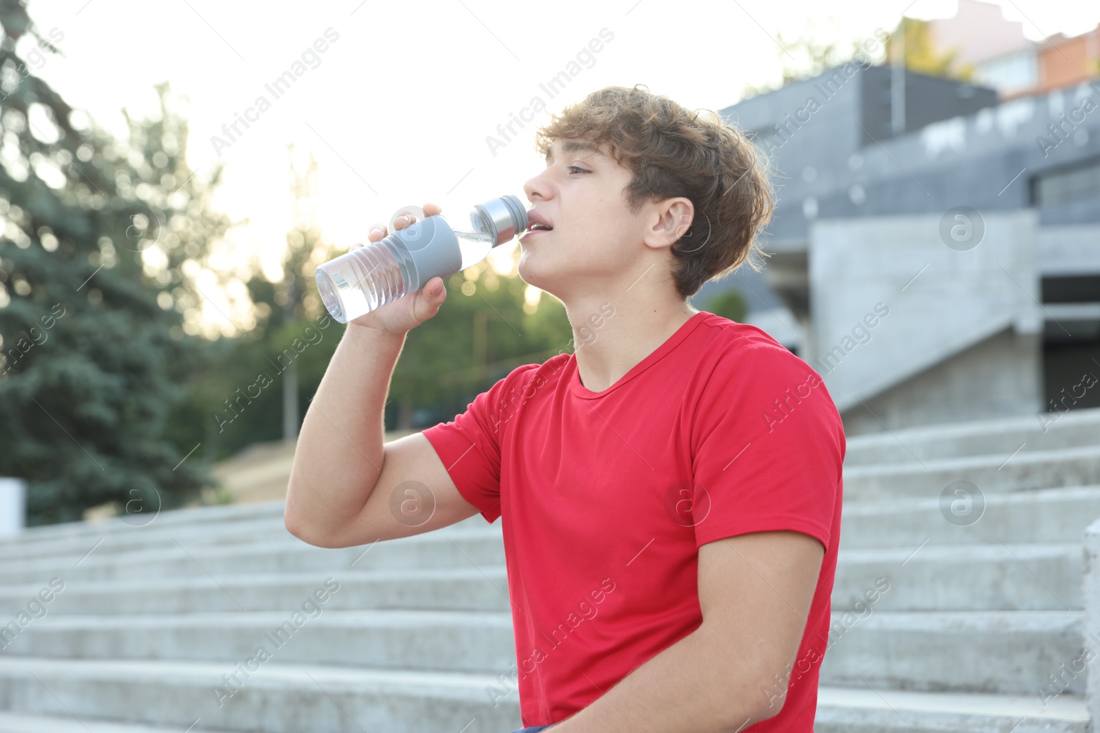 Teenage boy drinking water after training outdoors Photo of Teenage boy drinking water after training outdoors