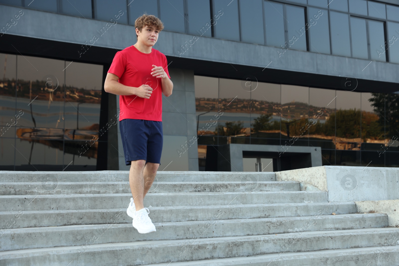 Teenage boy running down stairs outdoors. Space for text Photo of Teenage boy running down stairs outdoors. Space for text