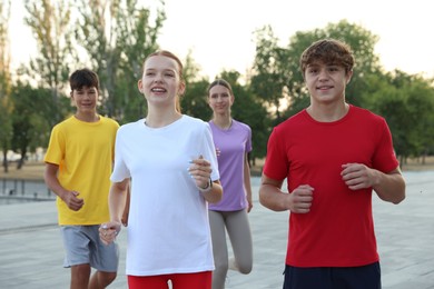 Photo of Group of teenagers jogging outdoors. Morning run
