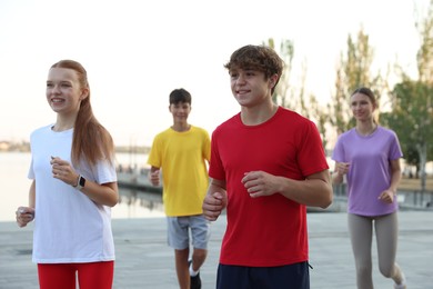 Photo of Group of teenagers jogging outdoors. Morning run