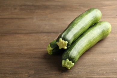 Photo of Fresh ripe zucchinis on wooden table, closeup. Space for text
