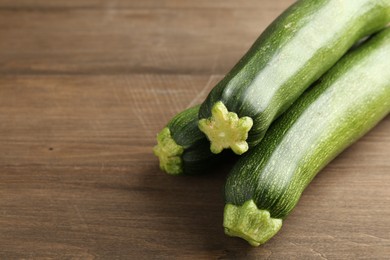 Photo of Fresh ripe zucchinis on wooden table, closeup. Space for text
