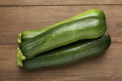 Photo of Fresh ripe zucchinis on wooden table, top view