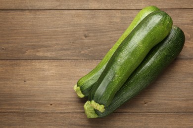 Photo of Fresh ripe zucchinis on wooden table, top view. Space for text