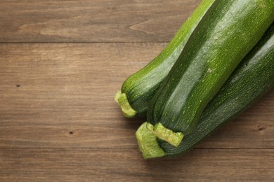Photo of Fresh ripe zucchinis on wooden table, top view. Space for text