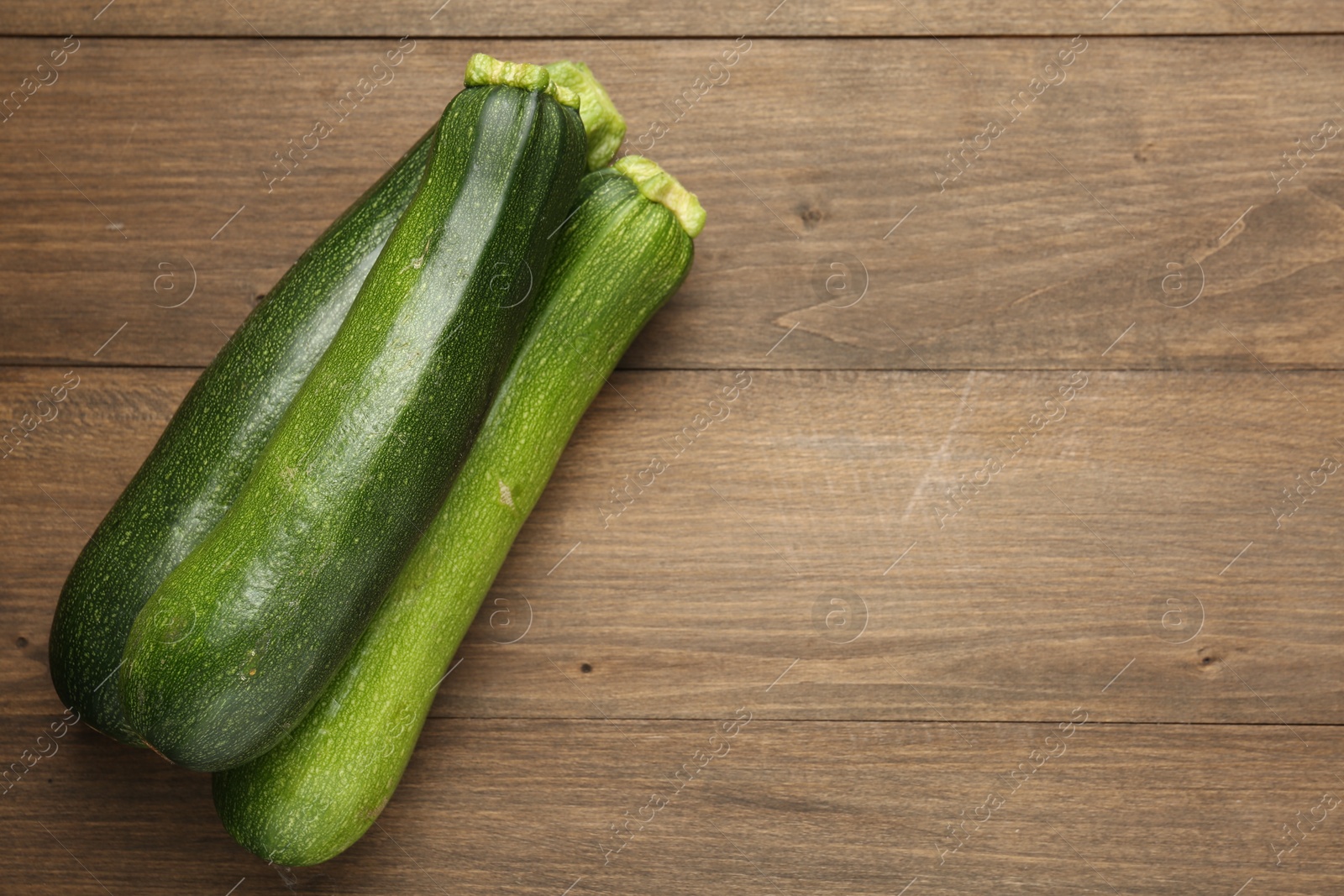 Fresh ripe zucchinis on wooden table, top view. Space for text Photo of Fresh ripe zucchinis on wooden table, top view. Space for text