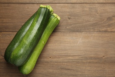 Photo of Fresh ripe zucchinis on wooden table, top view. Space for text