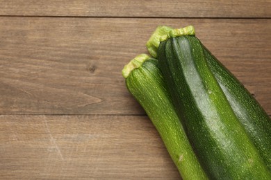 Photo of Fresh ripe zucchinis on wooden table, top view. Space for text