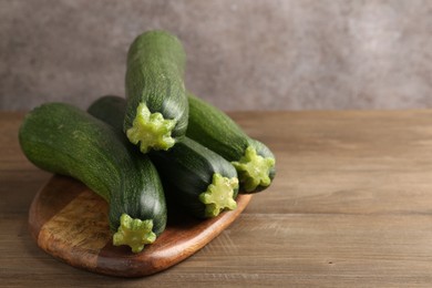 Photo of Fresh ripe zucchinis on wooden table, closeup. Space for text