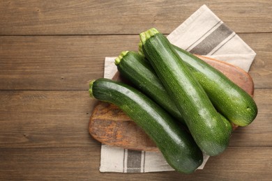 Photo of Fresh ripe zucchinis on wooden table, top view. Space for text