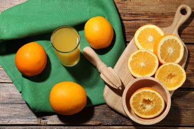 Photo of Freshly squeezed orange juice, fruits and juicer on wooden table, flat lay