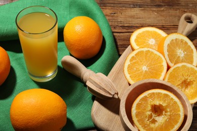 Photo of Freshly squeezed orange juice, fruits and juicer on wooden table, closeup