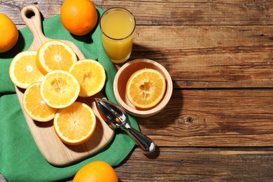 Photo of Freshly squeezed orange juice, fruits and juicer on wooden table, flat lay. Space for text
