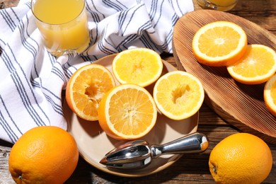 Photo of Freshly squeezed orange juice, fruits and juicer on wooden table, above view