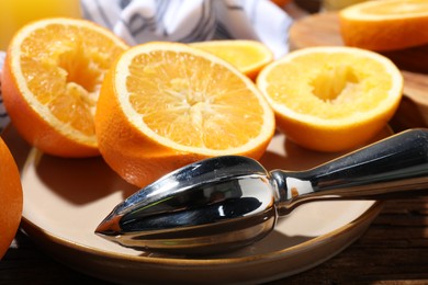 Photo of Making fresh juice. Juicer and oranges on wooden table, closeup