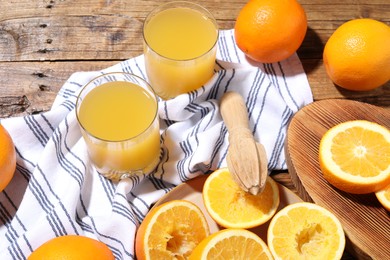 Photo of Freshly squeezed orange juice, fruits and juicer on wooden table, above view
