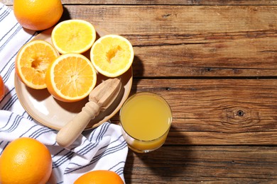 Photo of Freshly squeezed orange juice, fruits and juicer on wooden table, flat lay. Space for text