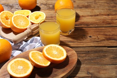 Photo of Freshly squeezed orange juice, fruits and juicer on wooden table, closeup. Space for text
