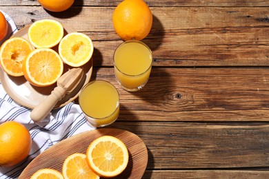 Photo of Freshly squeezed orange juice, fruits and juicer on wooden table, flat lay. Space for text