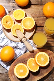 Photo of Freshly squeezed orange juice, fruits and juicer on wooden table, flat lay
