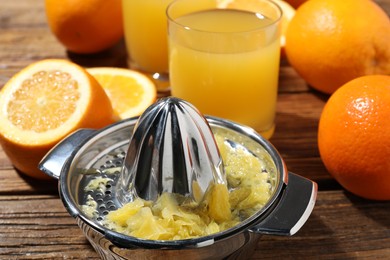 Photo of Freshly squeezed orange juice, fruits and juicer on wooden table, closeup