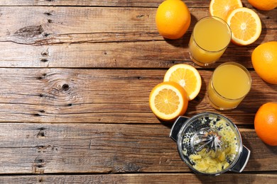 Photo of Freshly squeezed orange juice, fruits and juicer on wooden table, flat lay. Space for text