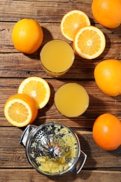 Photo of Freshly squeezed orange juice, fruits and juicer on wooden table, flat lay
