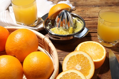 Photo of Freshly squeezed orange juice, fruits and juicer on wooden table, closeup