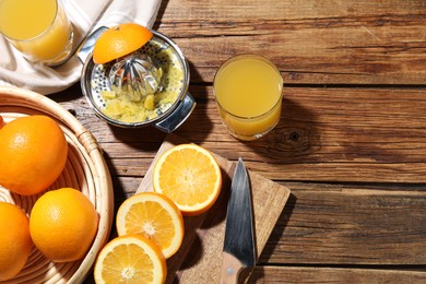 Photo of Freshly squeezed orange juice, fruits and juicer on wooden table, flat lay. Space for text
