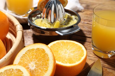 Photo of Freshly squeezed orange juice, fruits and juicer on wooden table, closeup